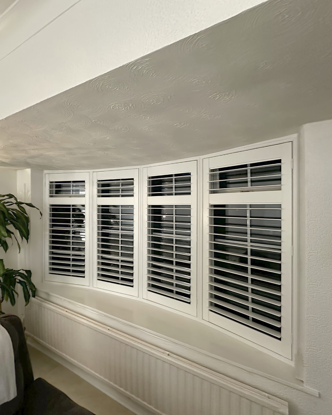 Full height shutters on a bay window in a dining area