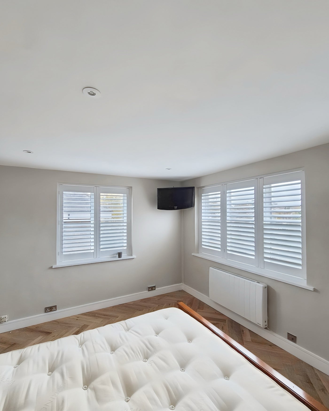 Full height shutters on a bay window and door panel in a bedroom