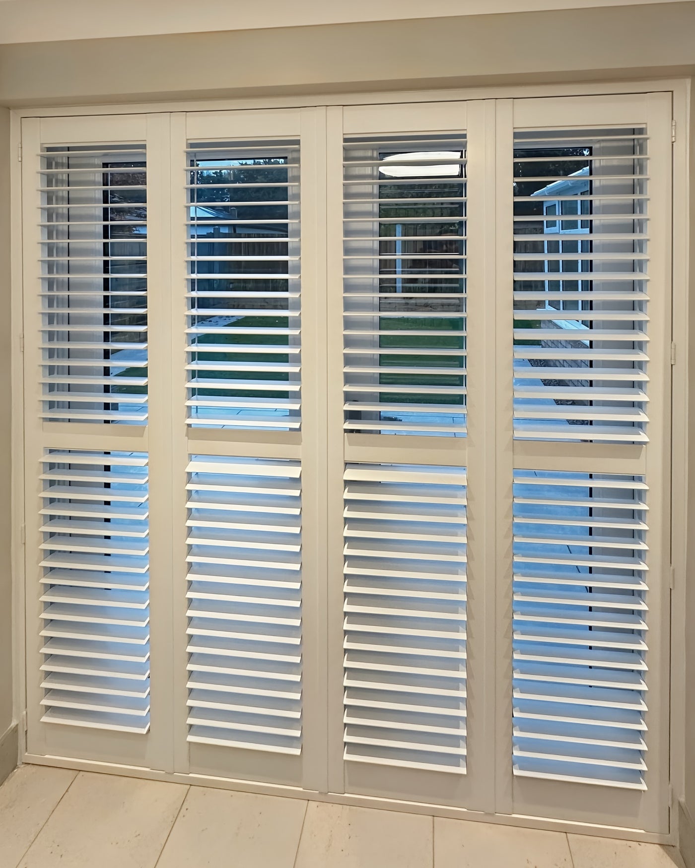 Tier-on-tier shutters across wide glazed doors opening onto a garden