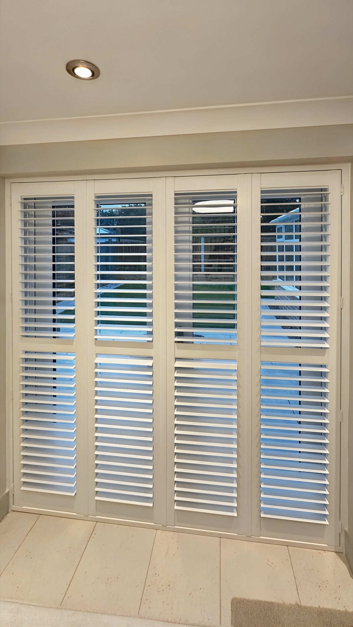 Tier-on-tier shutters across wide glazed doors, evening light
